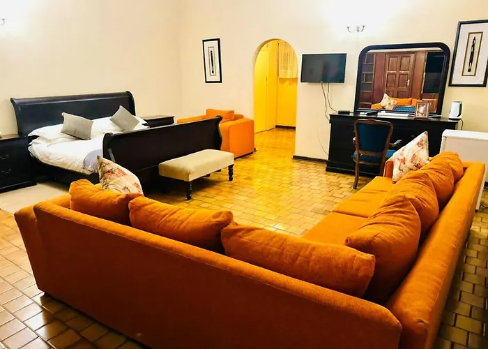 Signature suite lounge with sleigh bed and orange sofas at The White House Of Victoria Falls